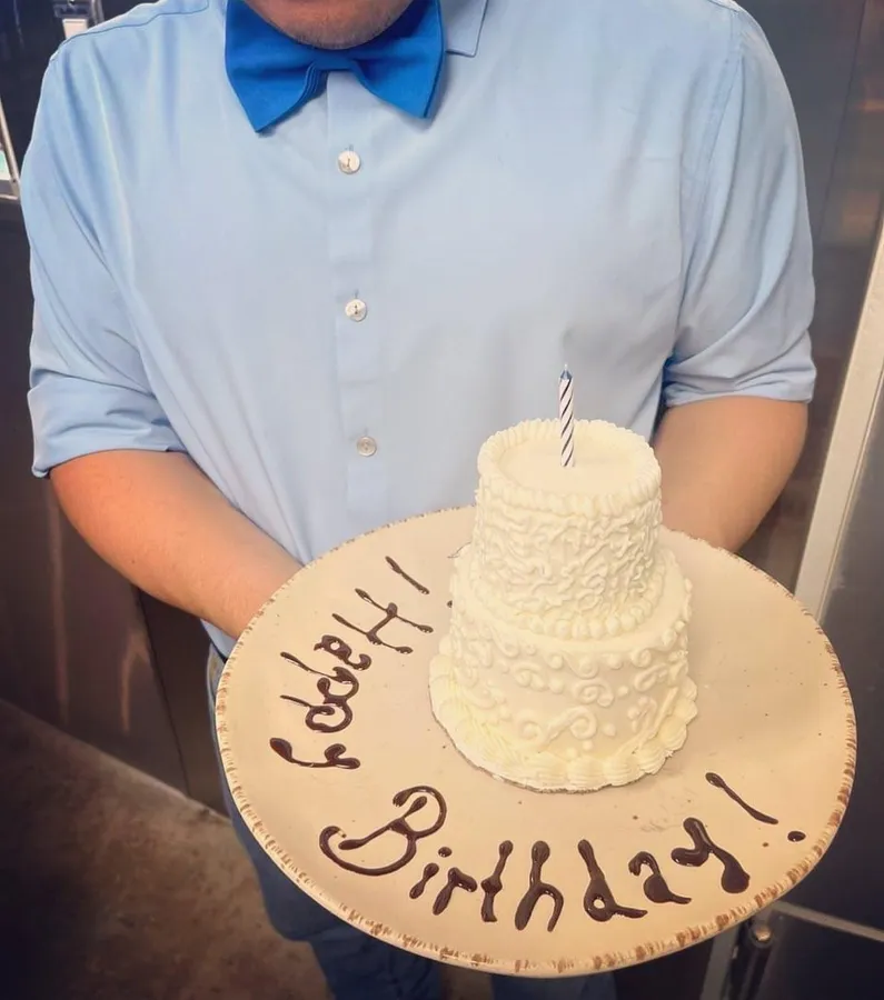 A mini tiered birthday cake on a Happy Birthday plate