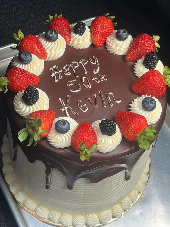 A chocolate cake with strawberries reading Happy 50th